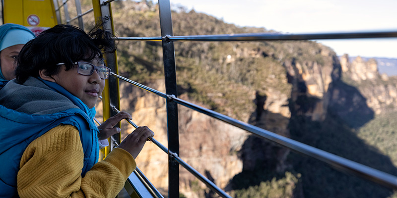 Young boy looks out of skyline gondola at three sisters in blue mountains NSW