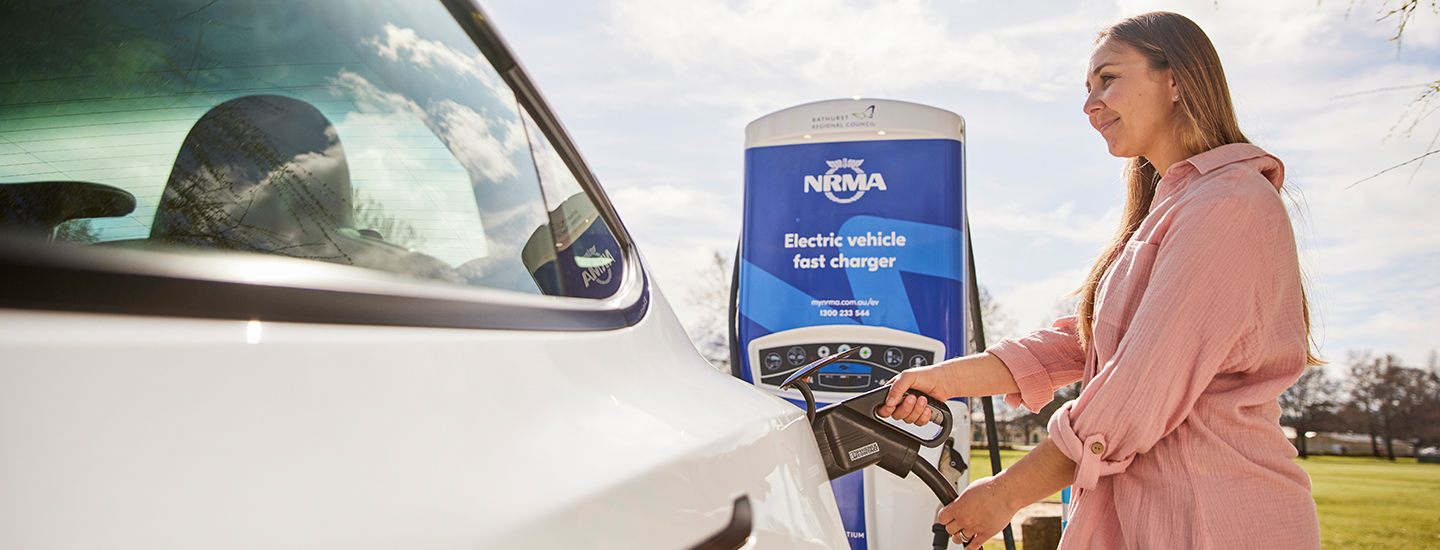 Woman charging EV at NRMA fast charger