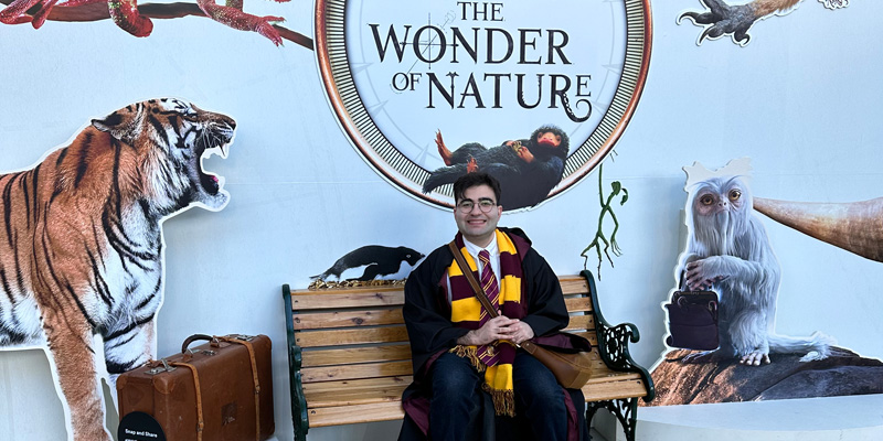 Man sitting on a bench smiling in front of exhibition sign