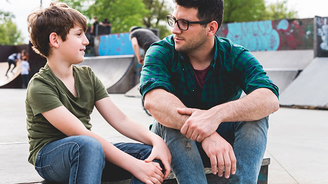 Father talking to his child at skate park