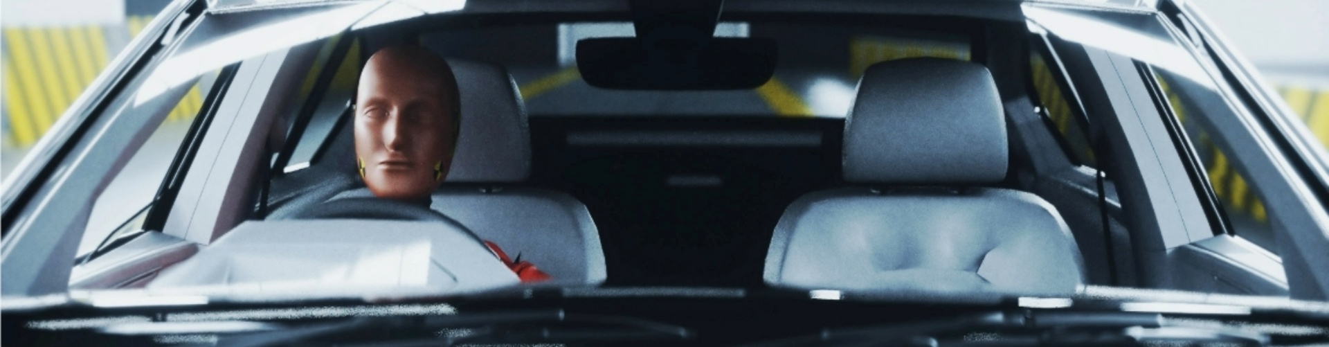 A crash test dummy sitting in the driver's seat of a car.