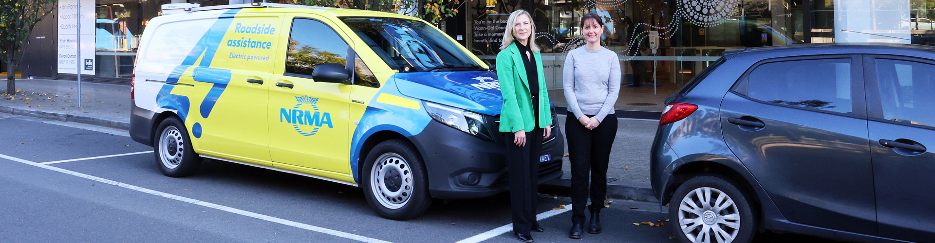 Two women standing beside an NRMA EV patrol van