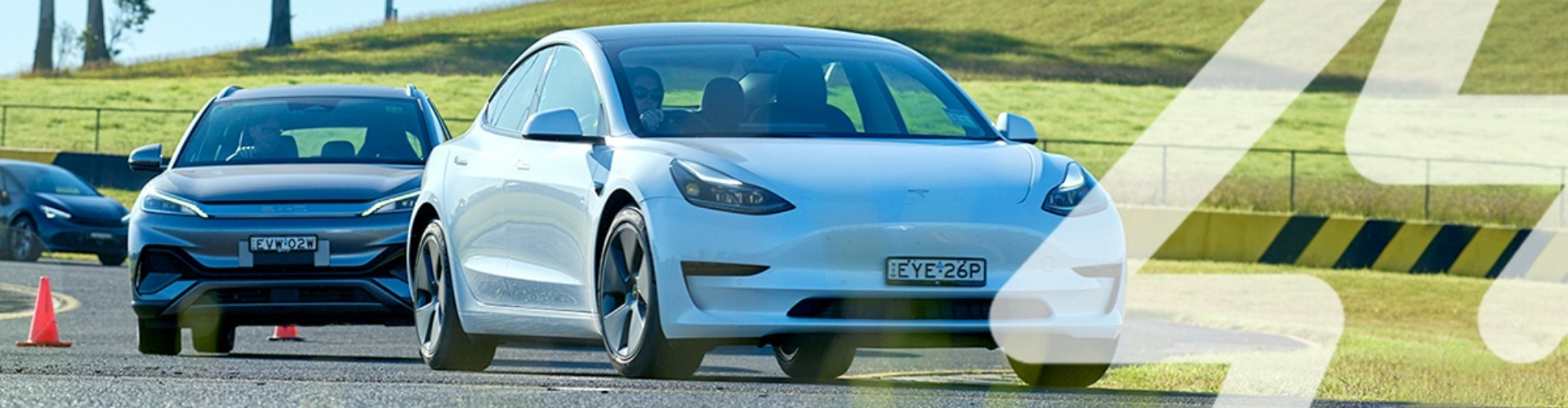 A line of electric vehicles driving on a track and avoiding orange cones.