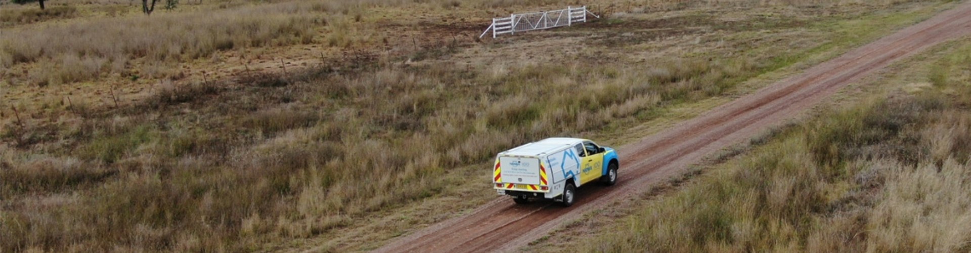 An NRMA vehicle driving along a dirt road in a remote, rural area.