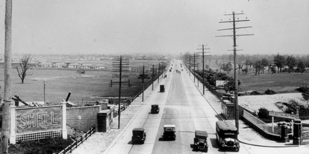 1920s black and white photograph showing an arial view of parramatta road with four lanes and vintage vehicles after the road had been improved