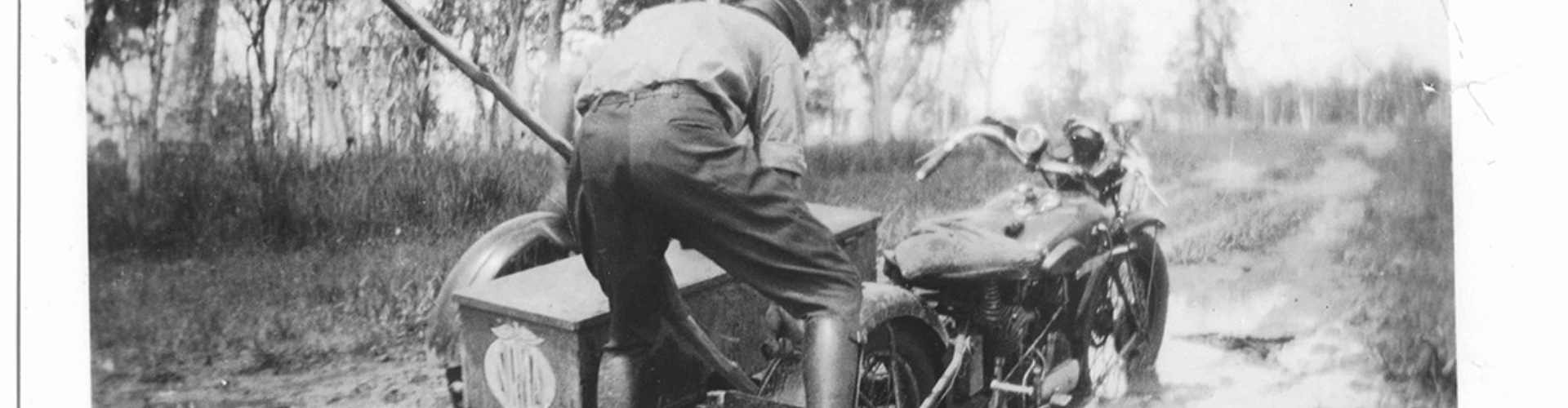 NRMA Roadside Patrol 1920s stuck in mud black and white photo of 1020s roadside patrolman easing bike out of deep mud with a tree branch