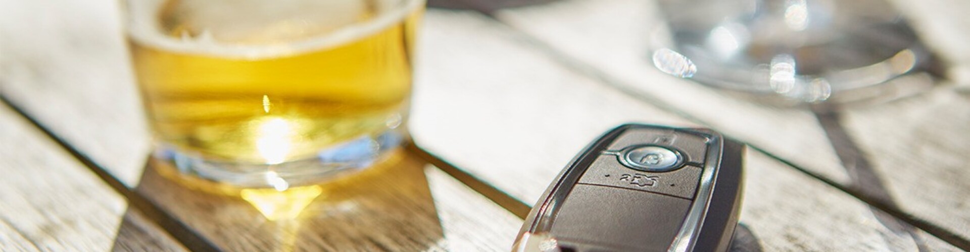 A key fob sitting beside an alcoholic drink