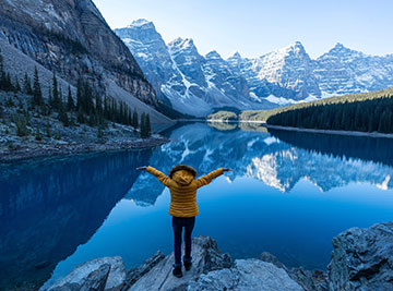 Lady with arms stretched out posing with the Canadian Rockies in front of her