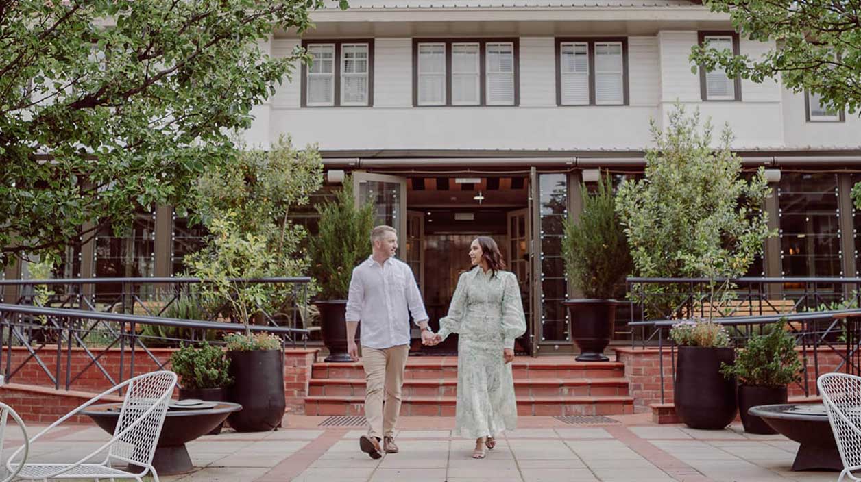 A couple joyfully holding hands in front of their Hotel accommodation, symbolising love and togetherness