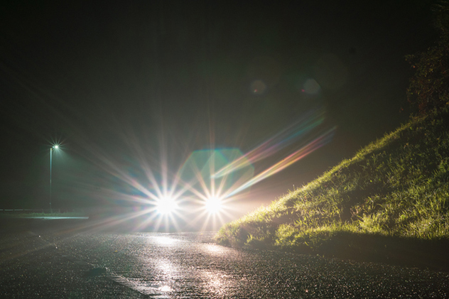Car using high beams on dark road