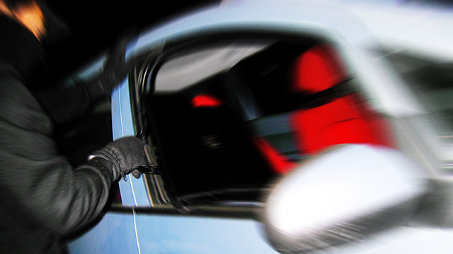 Man dressed in black breaking into car