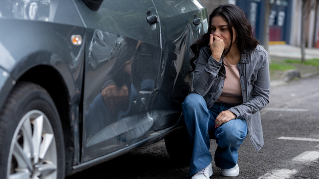 Crouching woman upset about her damaged car