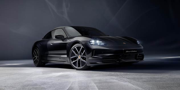 A black Porsche Taycan parked in front of a dark grey wall