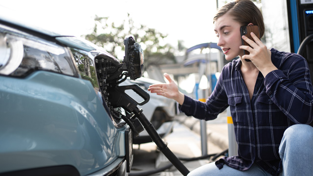 Woman call mobile phone about Accident and breakdowns with EV Charger at station. Broken down car, blonde woman having problem, calling to somebody for help. Worried person on phone while charging EV