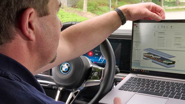 A man studies a screen with an image of a solid state battery while seated in a BMW