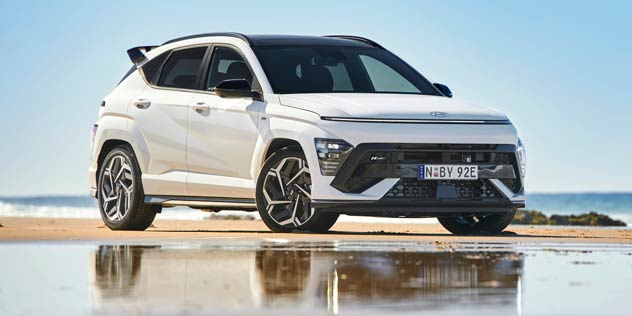 A white SUV parked on the beach with a reflection in the water
