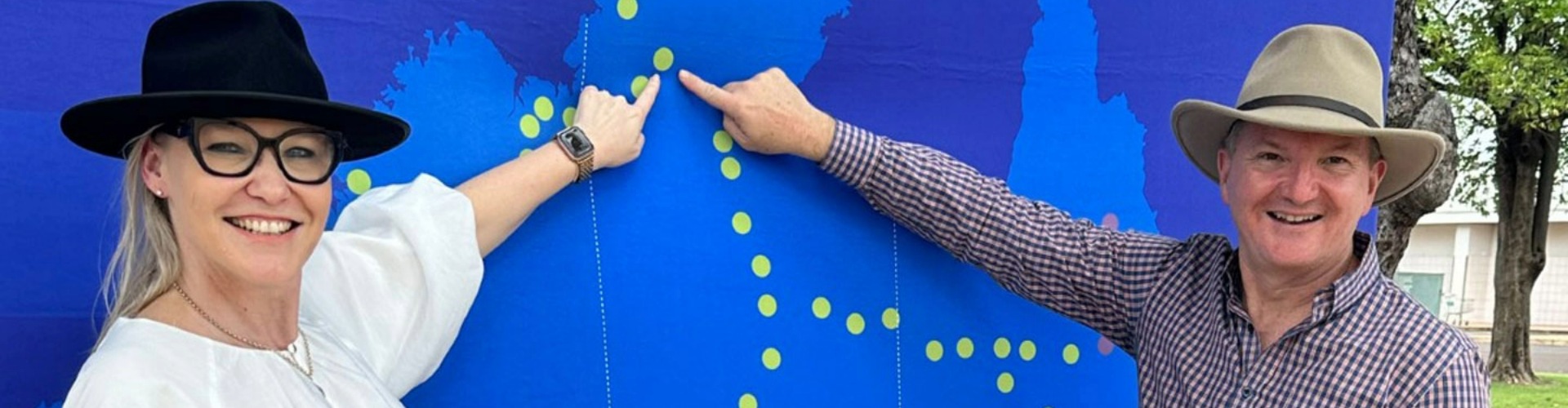A women and man standing in front of a big blue map and pointing to it.