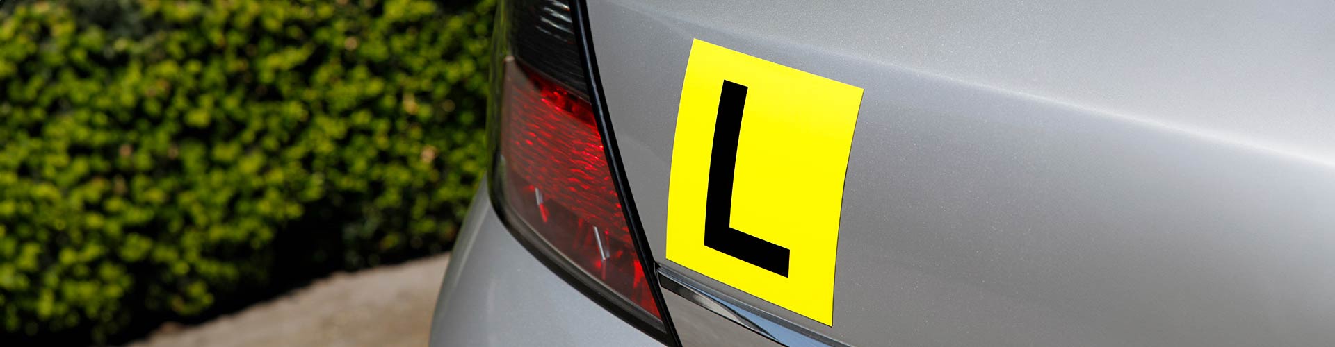 L plate on the rear of a silver grey car