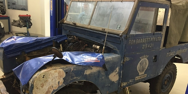 Front view of a blue and green classic car that's smashed up and needs restoration.