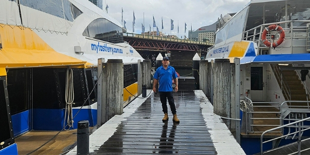 NRMA deckhand Thomas Wright standing on a wooden dock, between two boats.