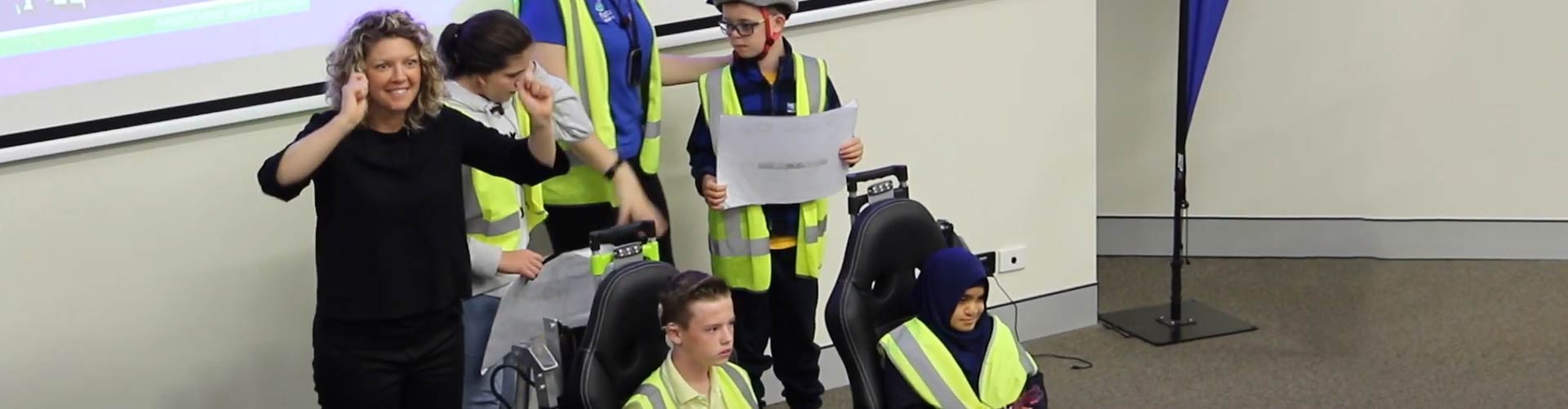 A woman signs to an unseen audience accompanied by deaf and blind children