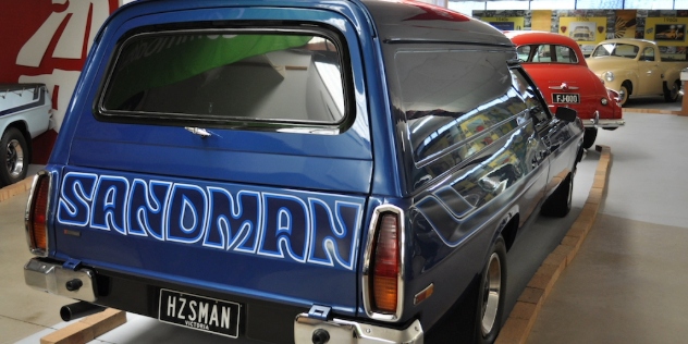 Rear view of a blue 1970 Panelvan parked in a showroom.