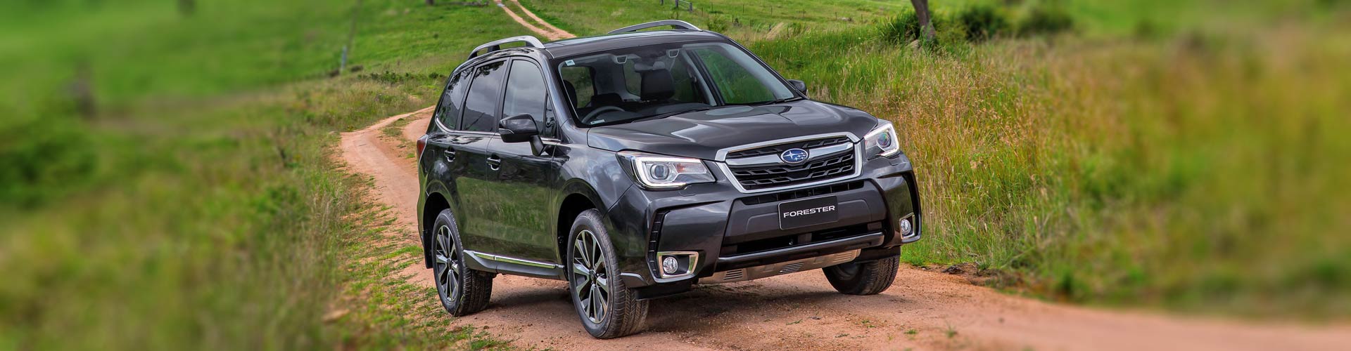 A black 2016 Subaru Forester XT Premium driving on a country road