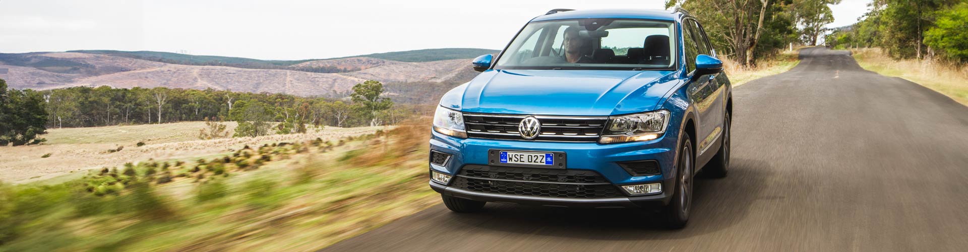 2016 Volkswagen Tiguan driving on a country road with gum trees in the background