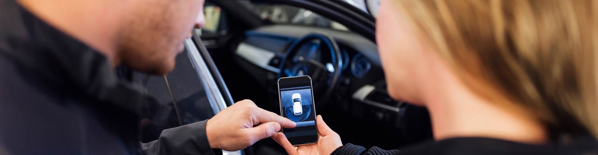 A man and woman look at a car app outside the vehicle