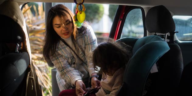 Mother putting her child into the child restraint car seat