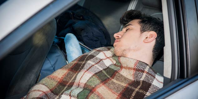 A young man sleeping in his car