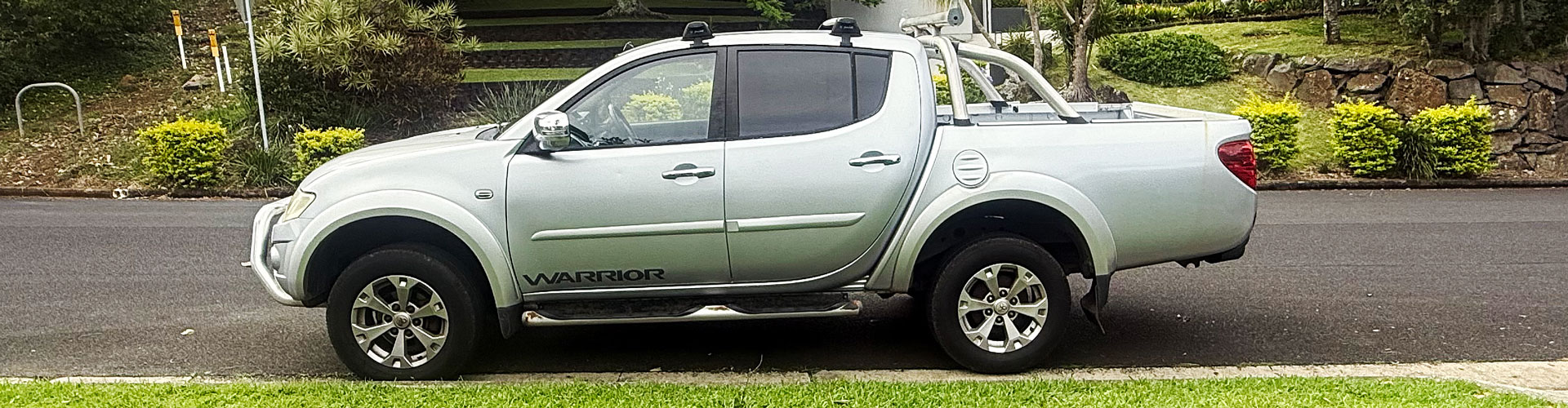 Side view of a sun-damaged Mitsubishi Triton parked on the road