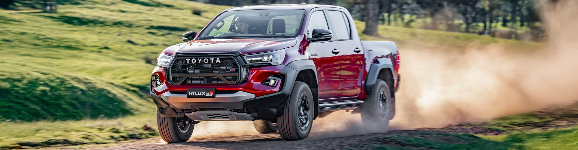 A red 2026 Toyota Hilux with dirt behind