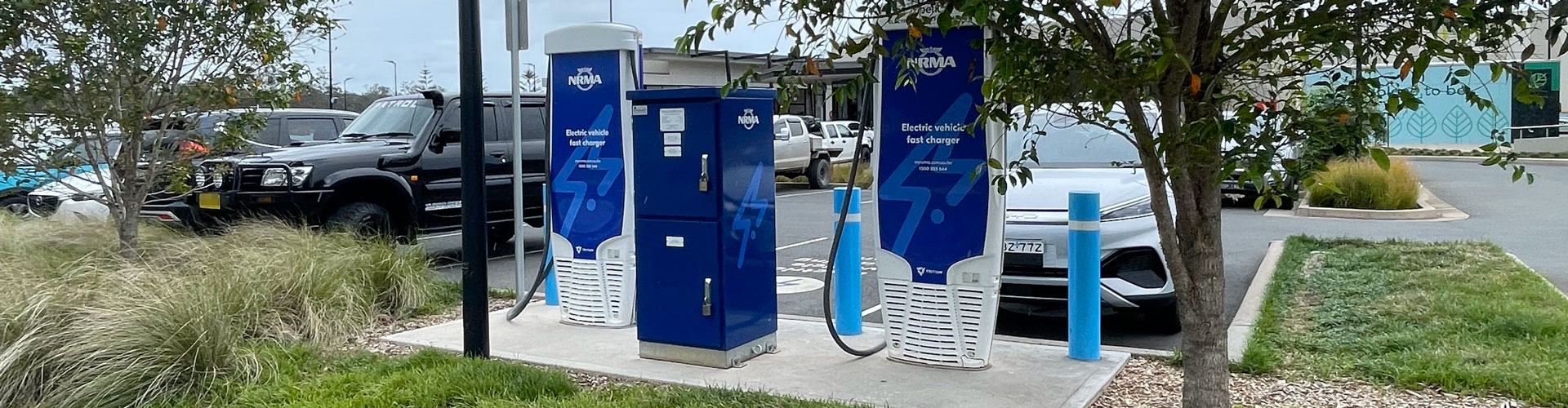 A BYD Atto 3 parked at the Thrumster NRMA EV charger with tree foliage hanging in front
