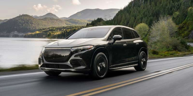 A dark coloured 2024 Maybach EQS680 drives along a mountainous lakeside road