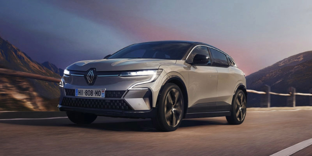 A 2024 Renault Megane Etech drives along a mountainous country road at dusk