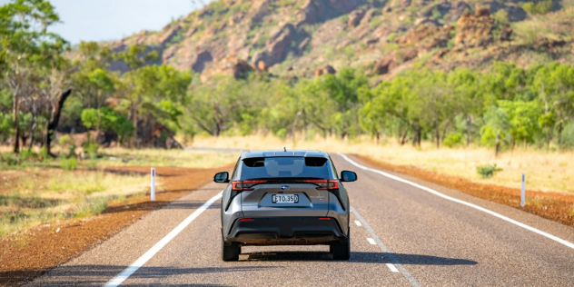 Rear view of a Toyota bZ4X driving on a road.