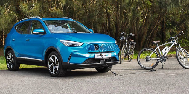 An MG ZS EV parked in the countryside charging an electric bicycle