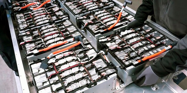 A factory worker inspects the inside of an EV battery 