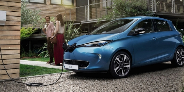 Blue Renault Zoe parked in front of a home entrance with a woman and man walking along the entrance path.