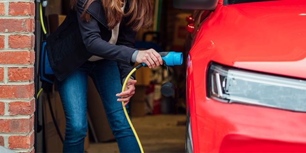 A person plugs their EV in to charge in the garage