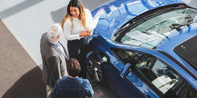 A salesperson discusses an electric vehicle with a couple