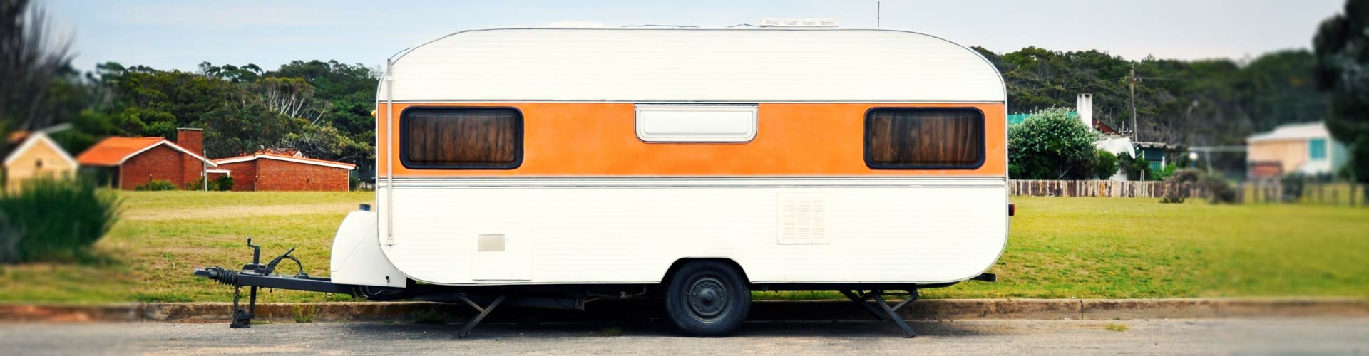 Orange and white caravan parked by the side of the road.