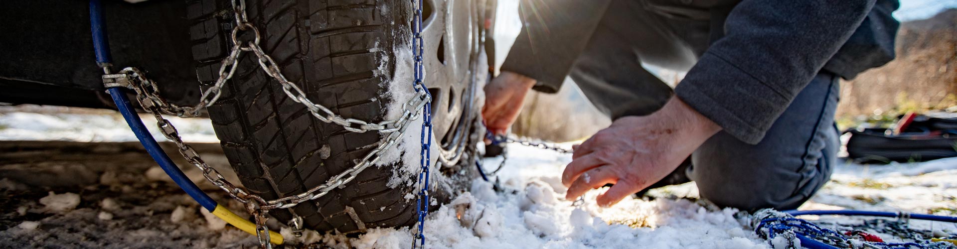 Adult Man Positioning Tire Chains on a Car