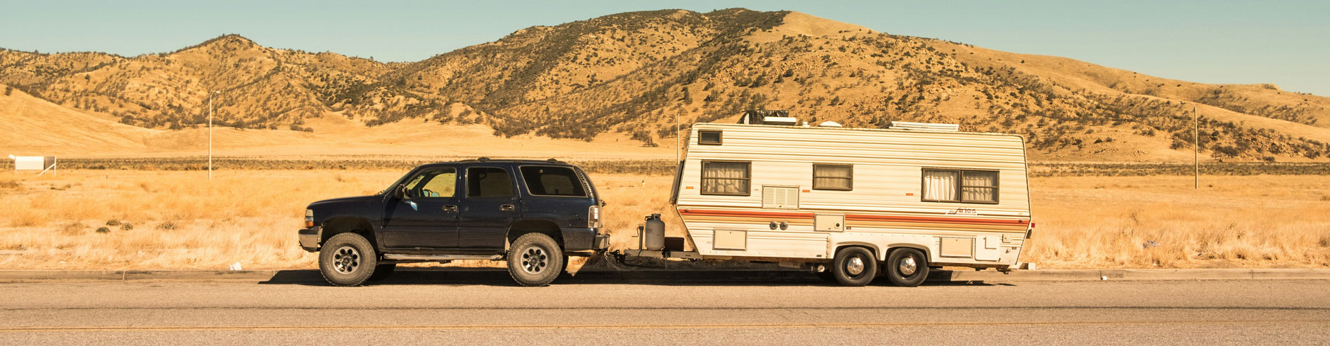 Black SUV towing a heavy caravan in the desert
