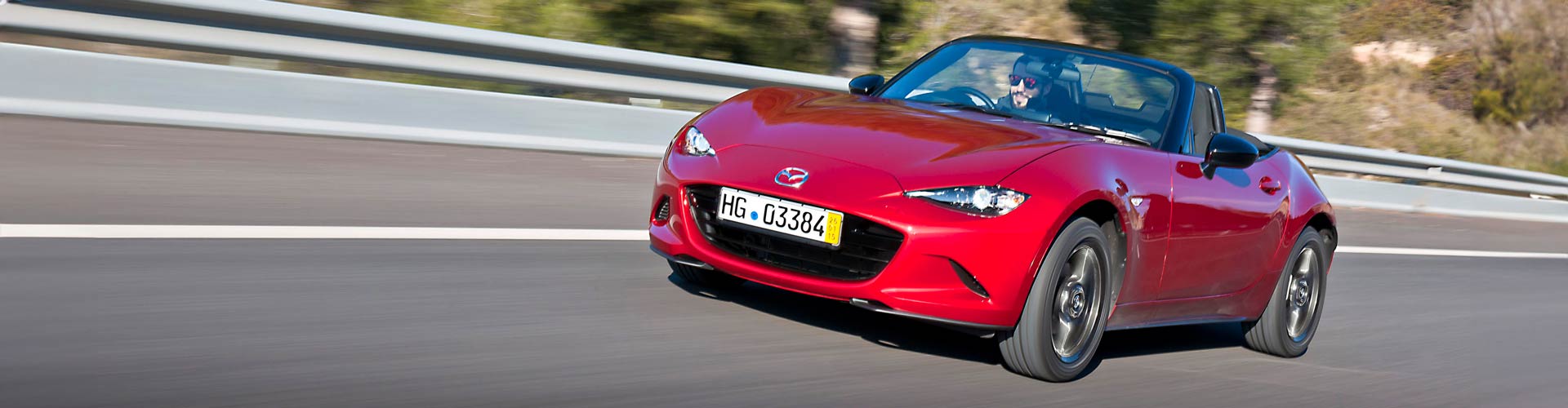 Red 2015 Mazda MX-5 NC-series driving on a road