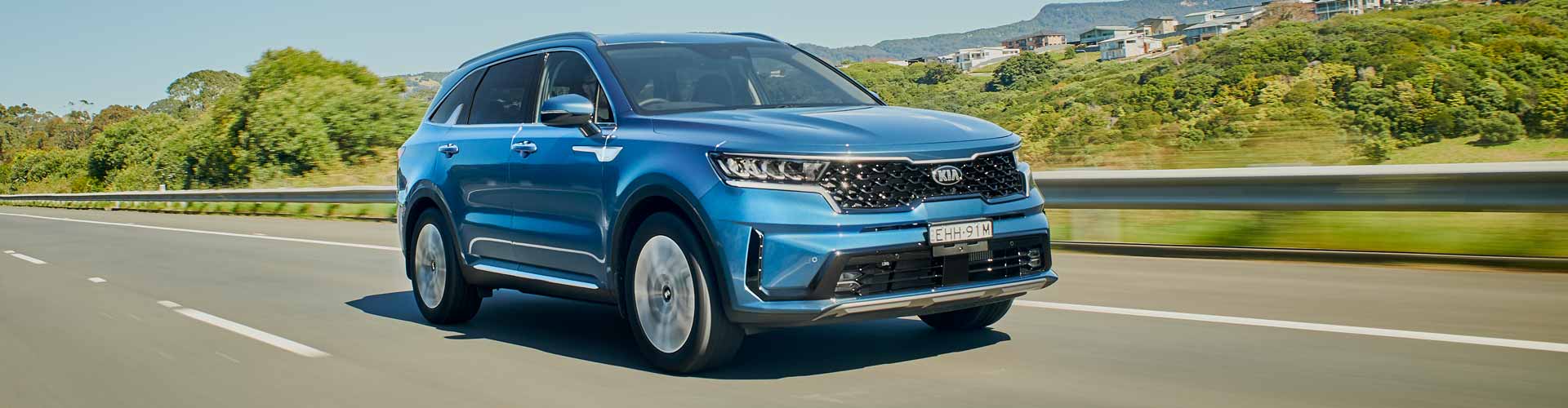 Blue 2020 Kia Sorento driving on a road past some trees