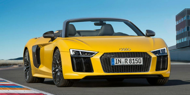 A sporty yellow Audi parked on a track with its top down.