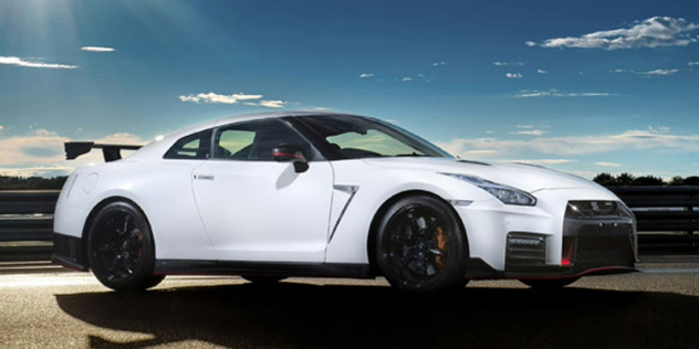 Side-angle view of a white, two-door car parked on a road with the sun glinting on it.