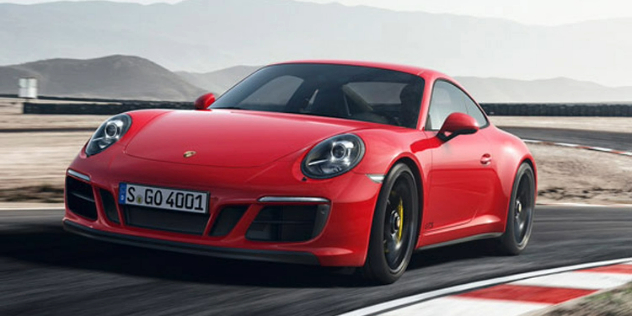 Front view of a red two-door porsche making its way around a track.